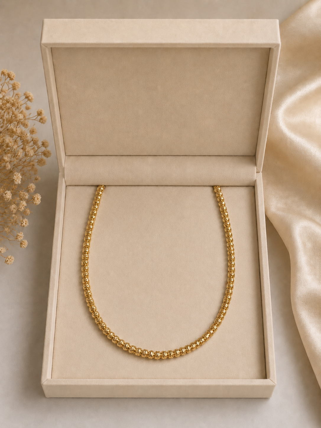 Collier billes dorées dans un coffret beige
